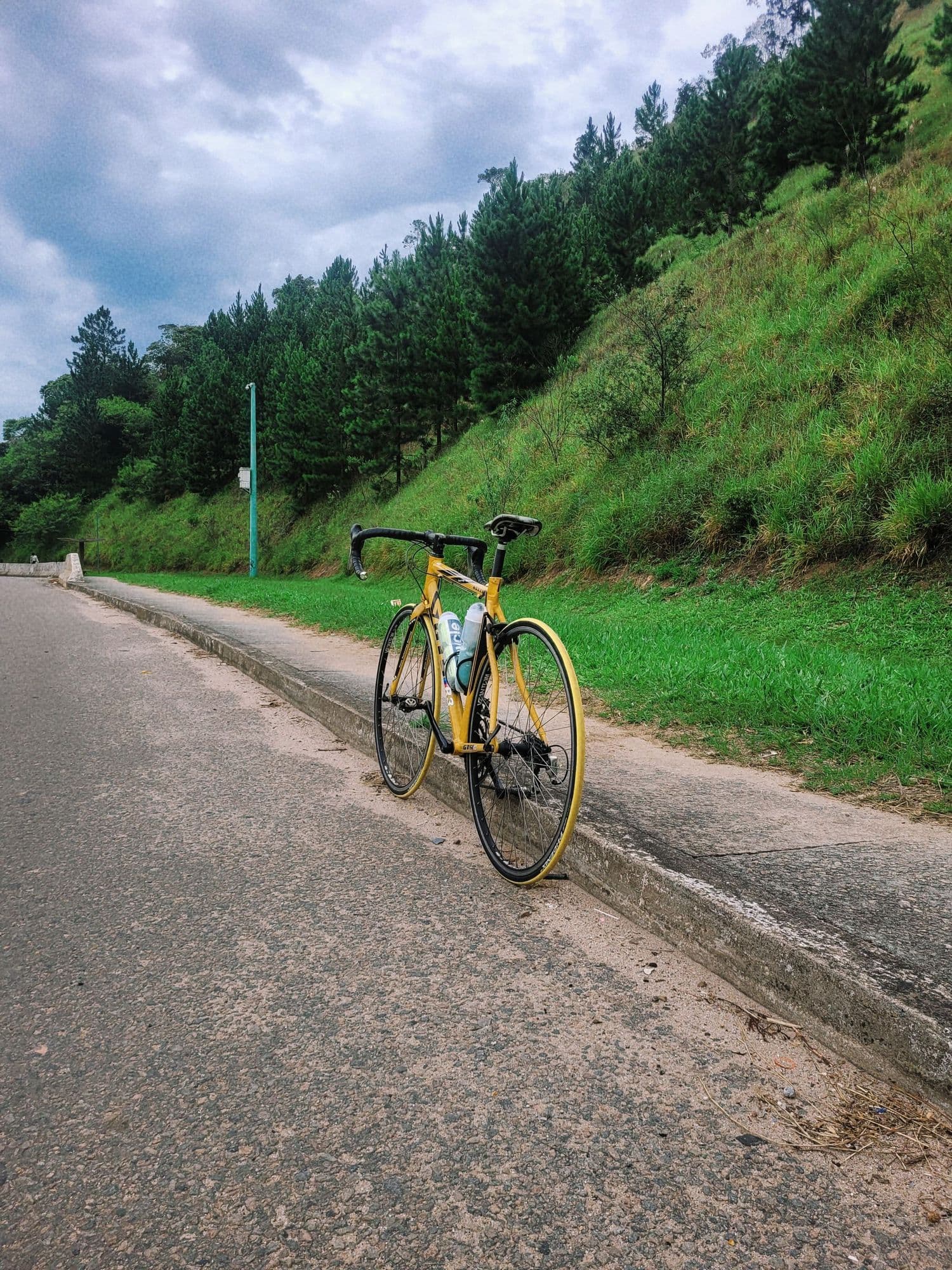 A cyclist on a quiet road along a green hillside
